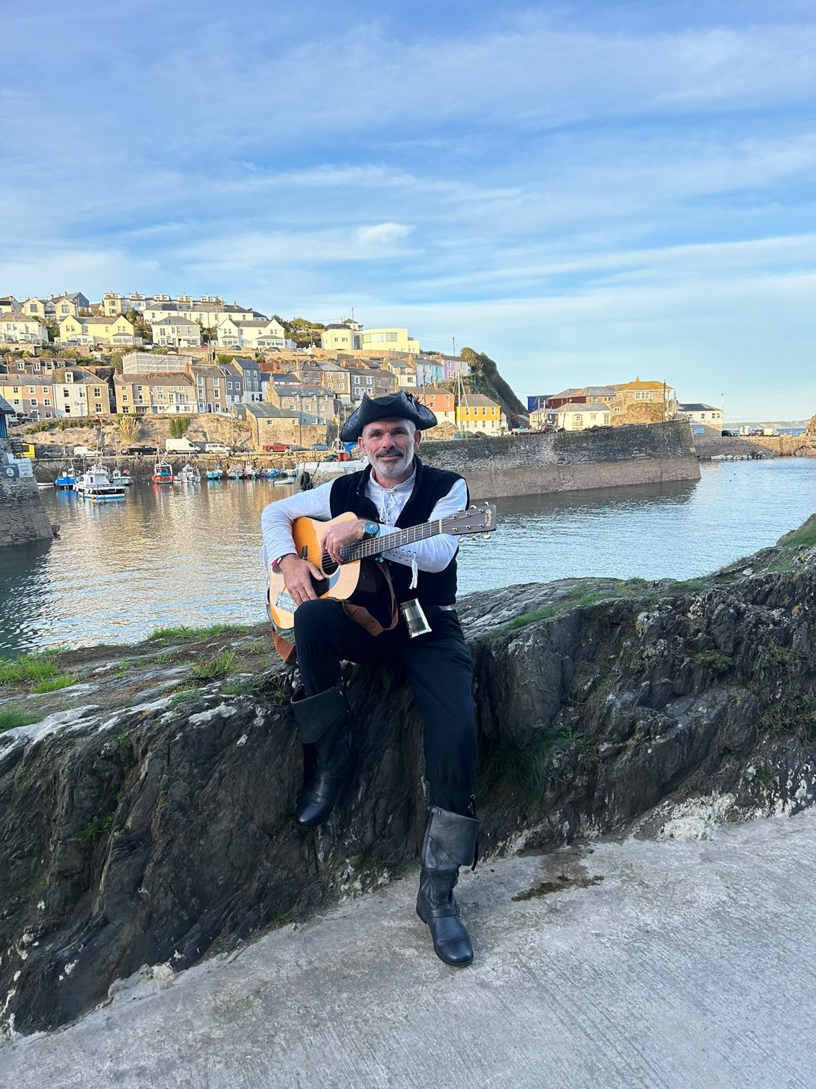 William Adams with his acoustic guitar overlooking a harbour